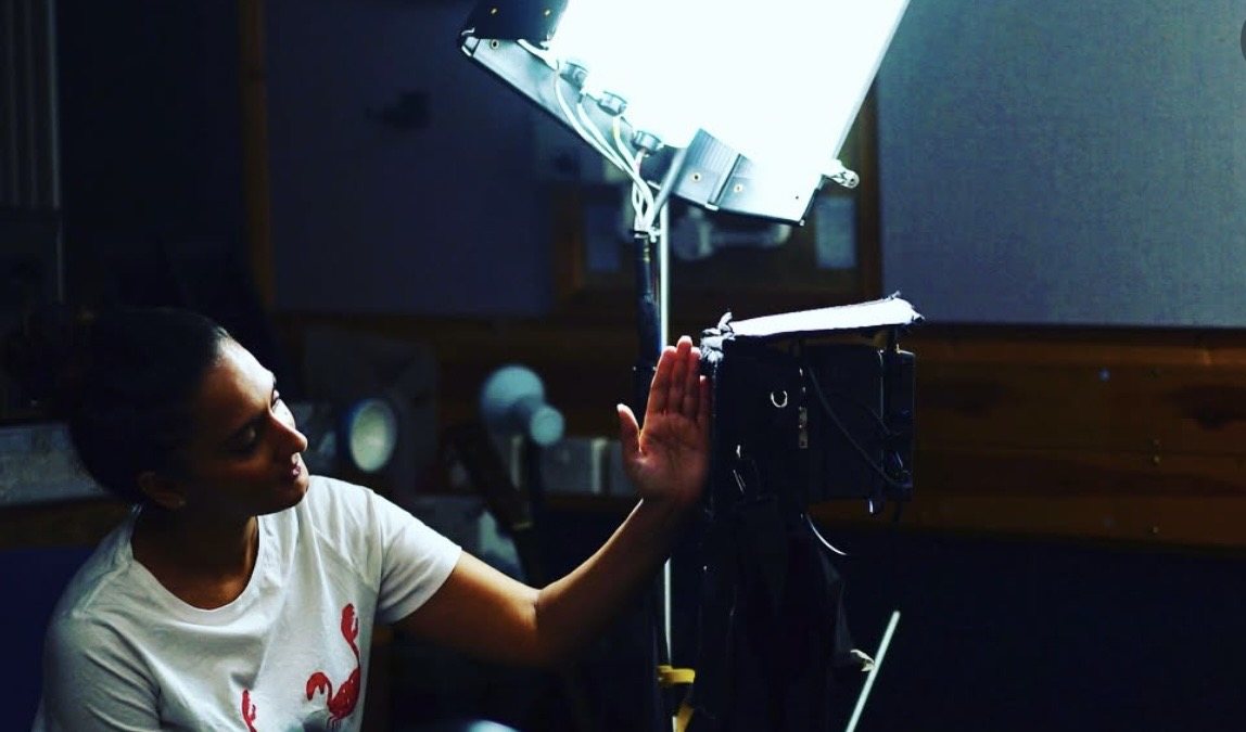 Maleena adjusting a light on set